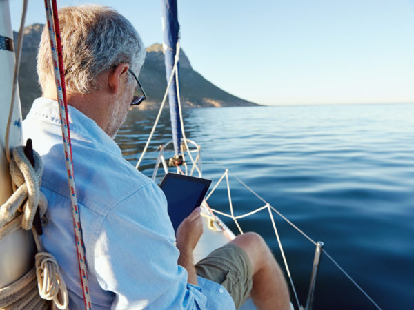 Older man using his tablet for retirement planning on his boat