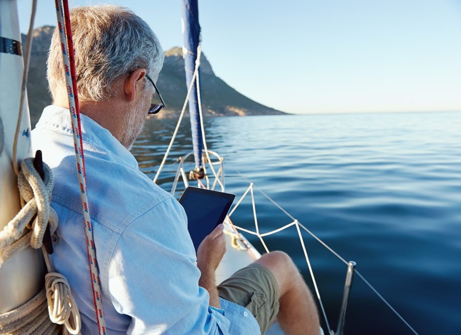 Older man using his tablet for retirement planning on his boat