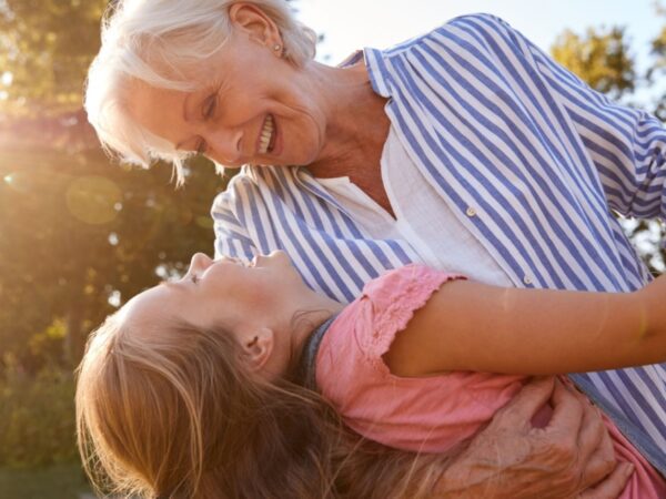 A grandmother playing with her granddaughter outside.