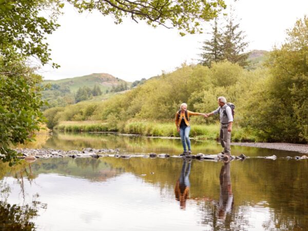A couple walking across stepping stones.