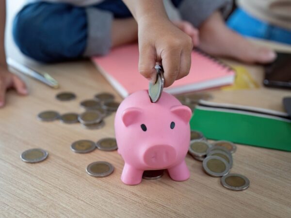 Child putting coins into a piggy bank