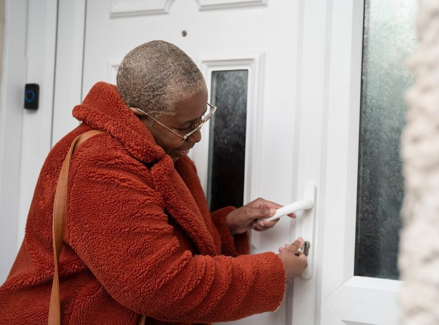 A woman unlocking a front door.