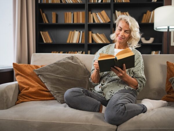Smiling lady sitting on a sofa reading a book