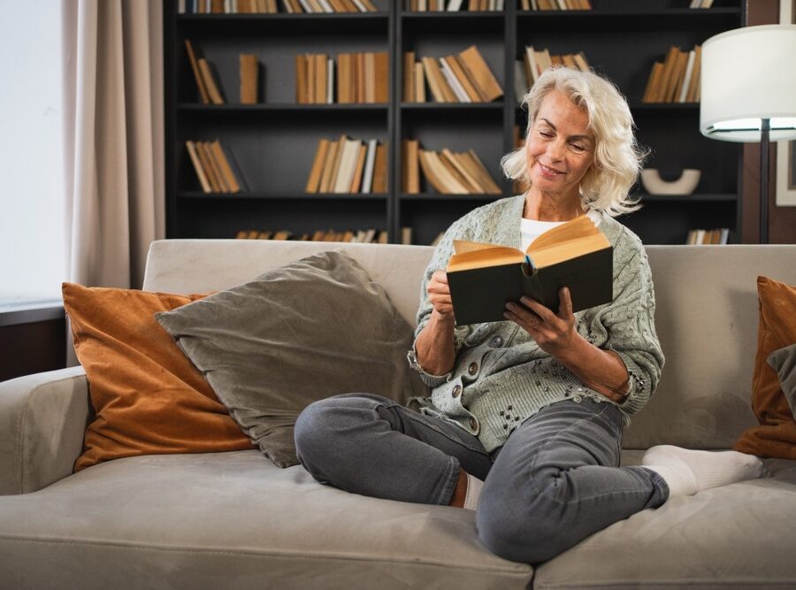 Smiling lady sitting on a sofa reading a book
