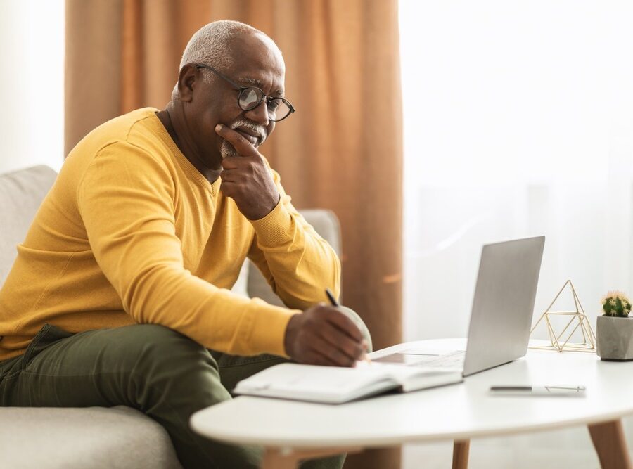 A man writing notes at a coffee table.