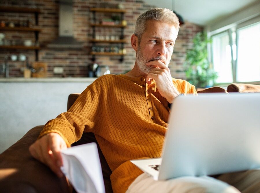A man in his 50s thinking while using a laptop