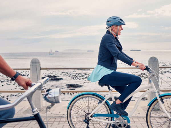 A woman cycling along a beachfront.