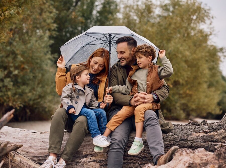 A young family sheltering under an umbrella and smiling