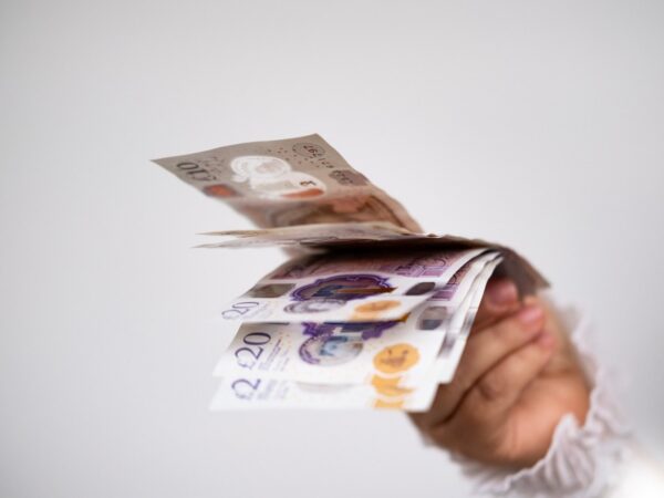 A hand holding UK bank notes.