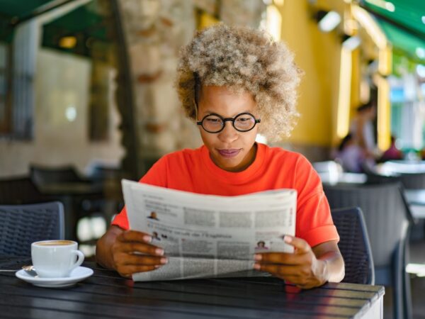 A woman reading a newspaper in a café.
