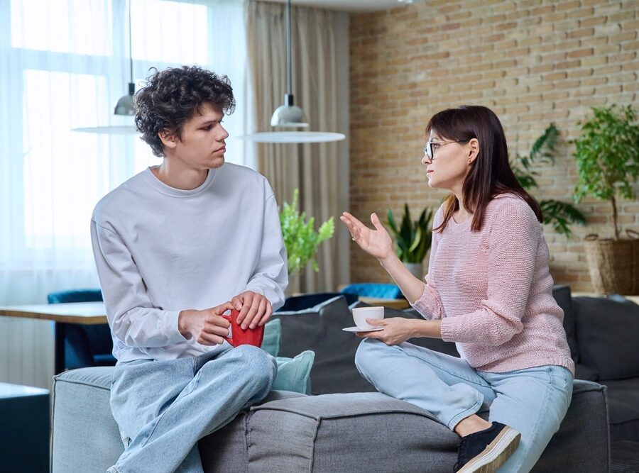 Middle-aged mother talking to her 18-year-old son at home